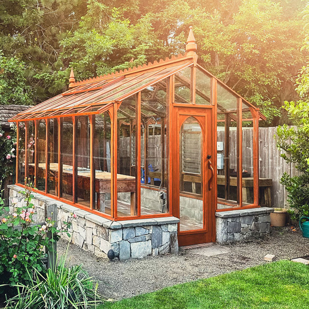 Wooden greenhouse with stone foundation in a garden setting
