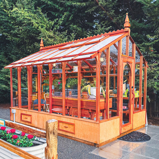 Wooden Artisan greenhouse with glass panels in a garden setting