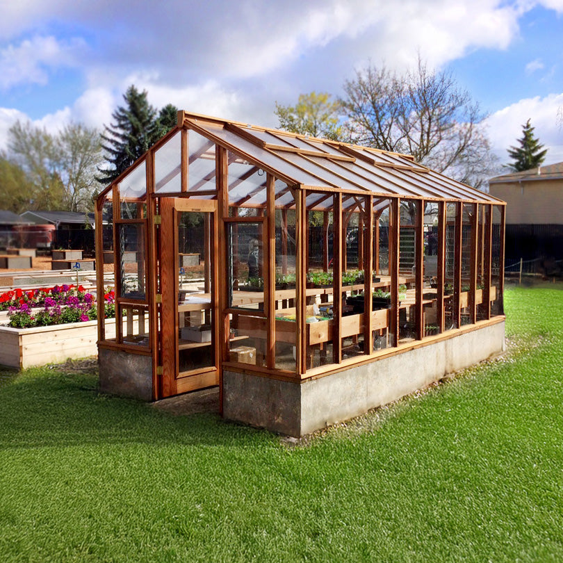 Wooden Artisan greenhouse with glass panels on a grassy area