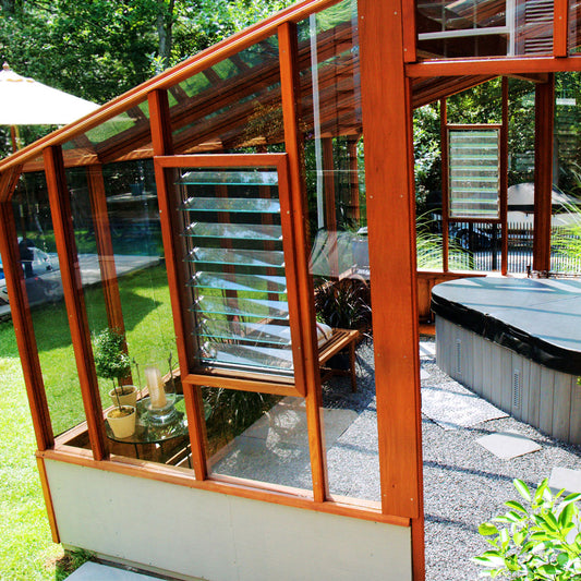 Outdoor patio area with a glass-enclosed seating area and hot tub.