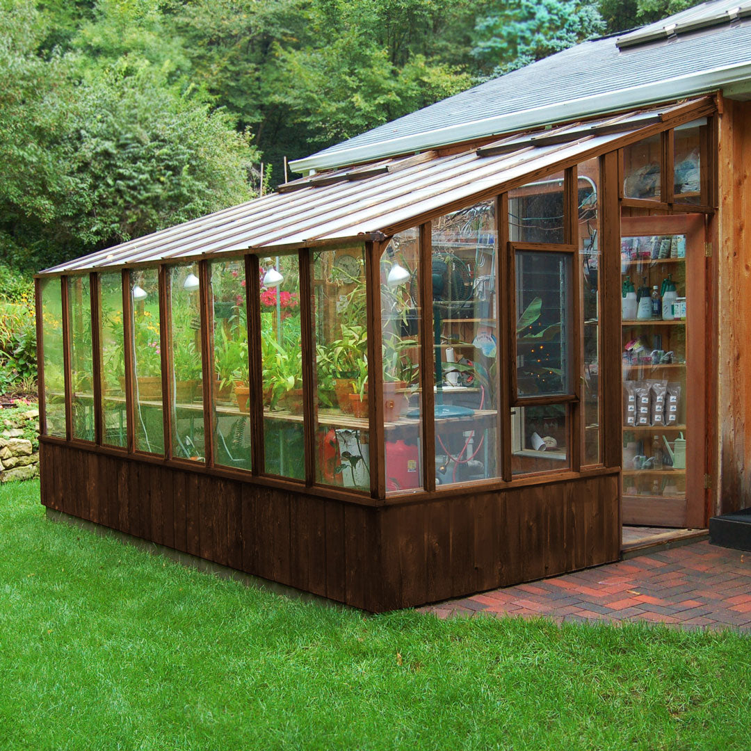 Wooden greenhouse with glass panels on a grassy area