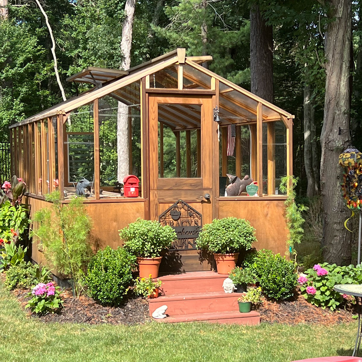 Wooden Heirloom greenhouse with plants and flowers in a garden setting
