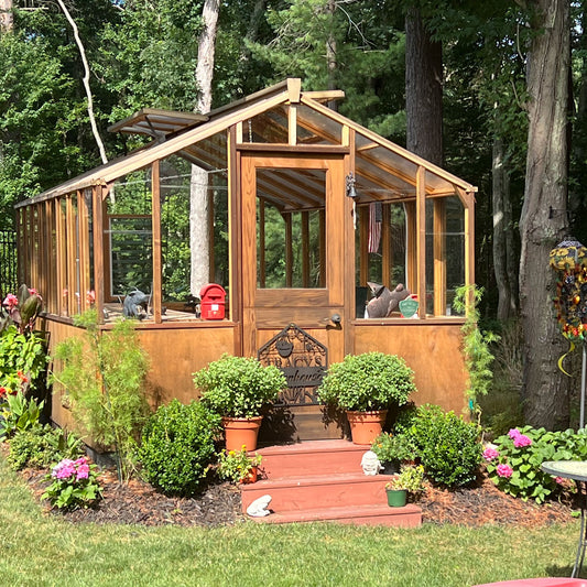 Wooden Heirloom greenhouse with plants and flowers in a garden setting