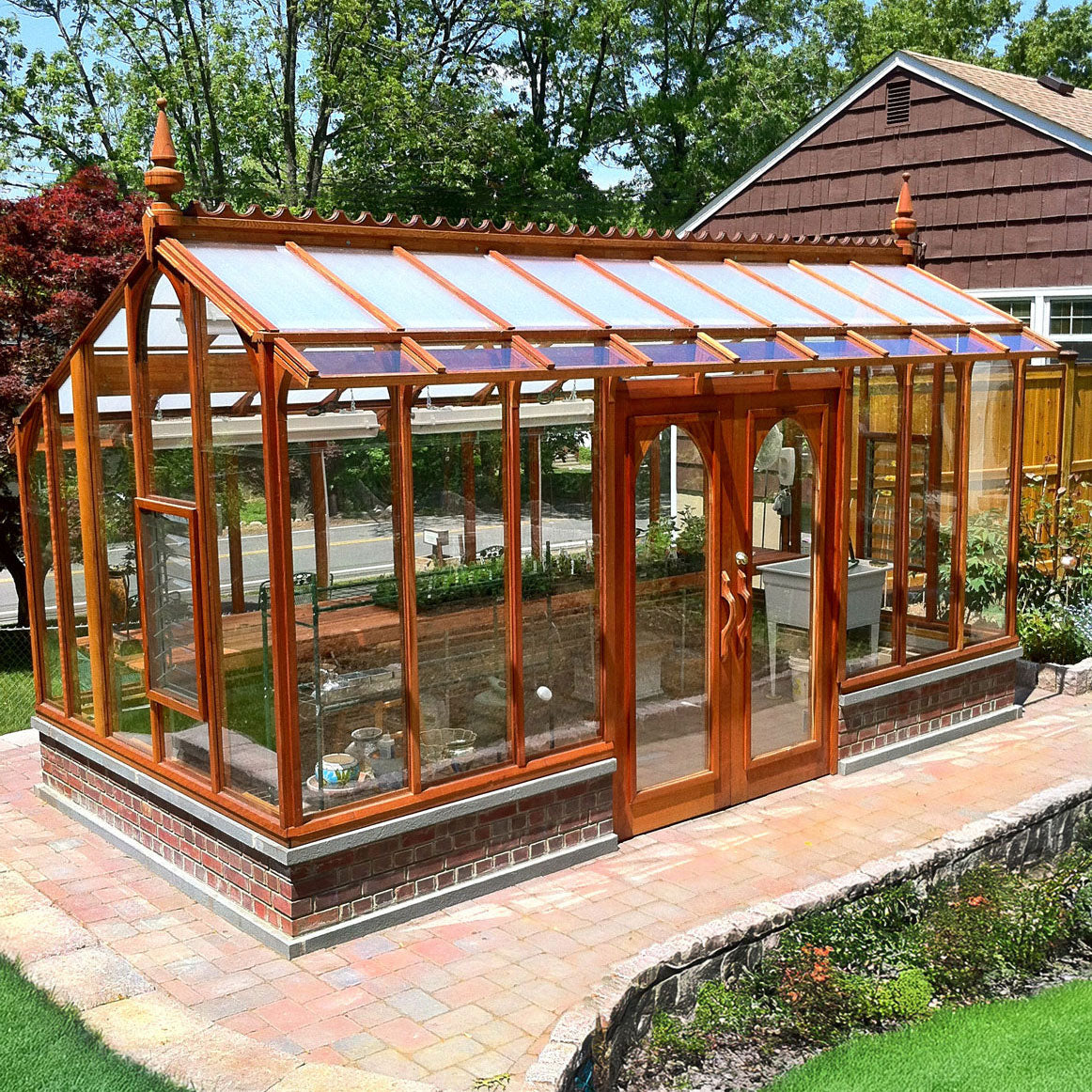 Wooden framed Nantucket greenhouse with glass panels on a patio