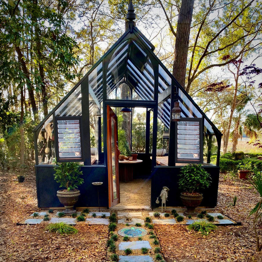 Tudor Greenhouse with black ridge accents and frosted glass in fall setting.
