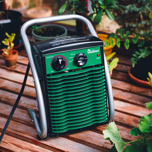 Green and black portable air conditioner on a wooden surface with plants around