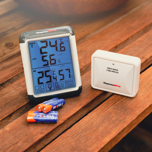 Digital thermometer and sensor on a wooden surface with batteries.