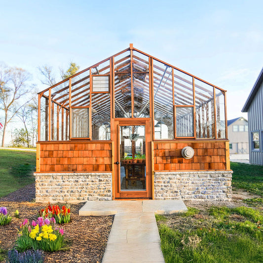Exterior photo of a wood-framed greenhouse with glass panels surrounded by a winter garden.