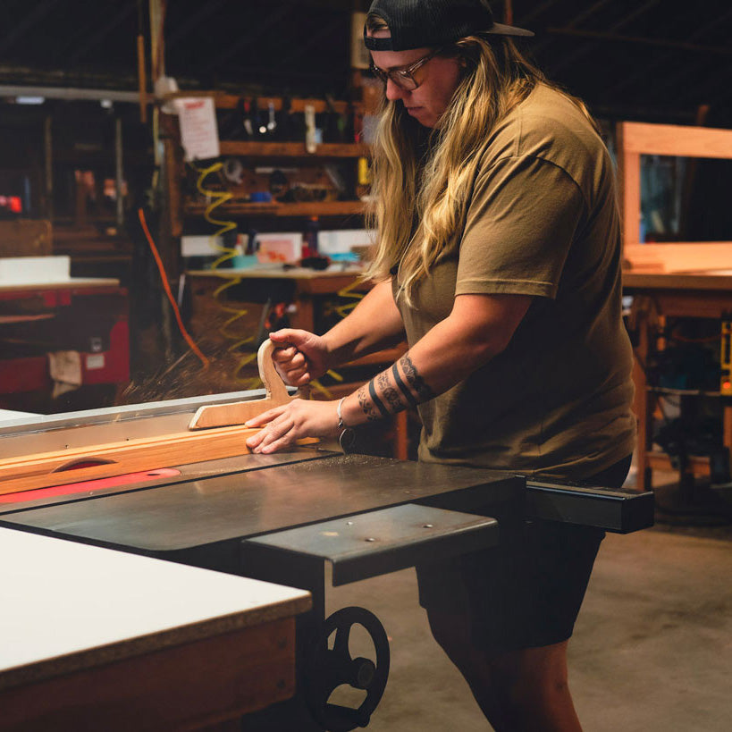Person operating a table saw in a greenhouse workshop