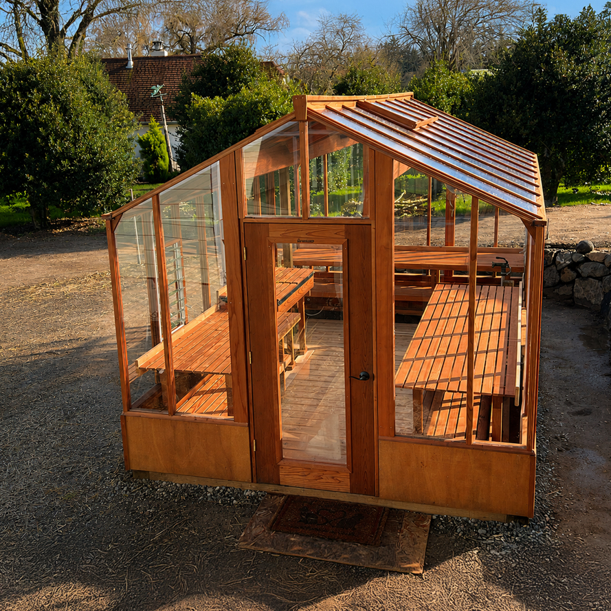 Wooden greenhouse with glass panels in a garden setting