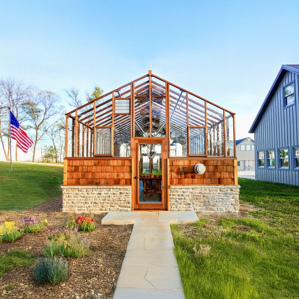 Wooden greenhouse with stone foundation in a garden setting