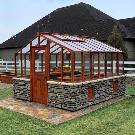 Wooden Heirloom greenhouse with stone foundation on a grassy lawn