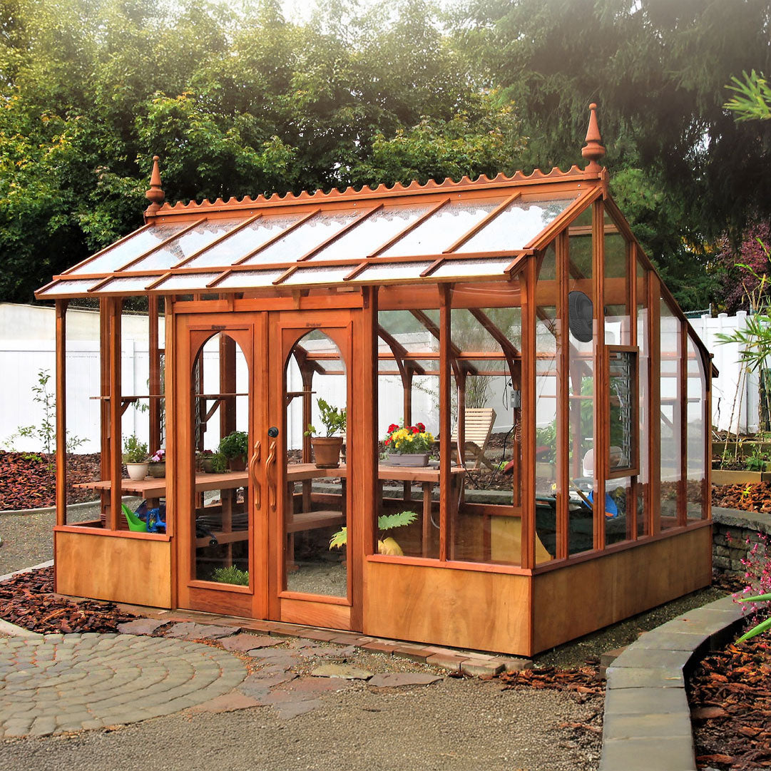 Wooden Nantucket greenhouse with glass panels in a garden setting