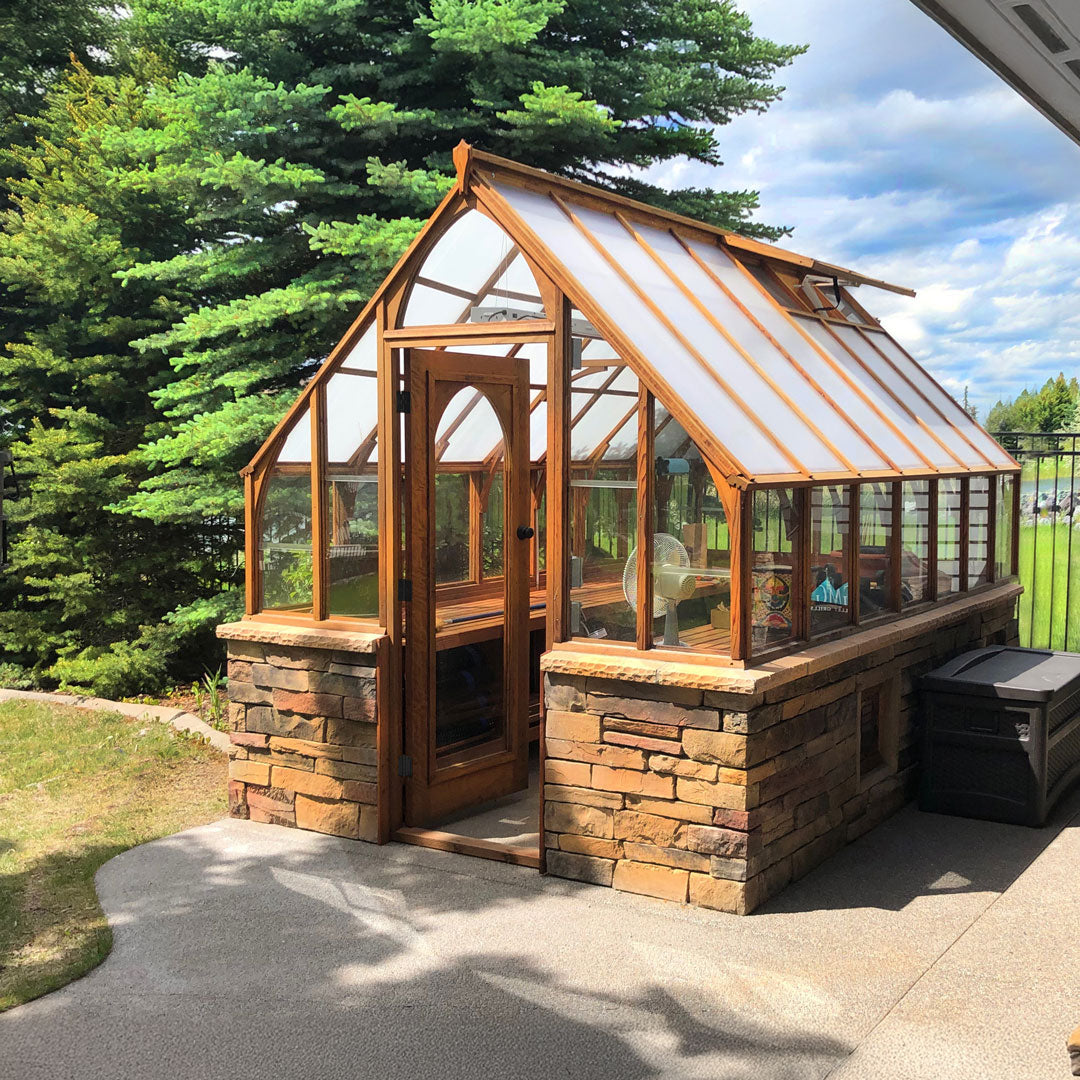 Wooden greenhouse with stone foundation in a garden setting