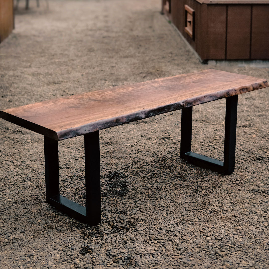 Wooden bench with black metal legs on a gravel surface