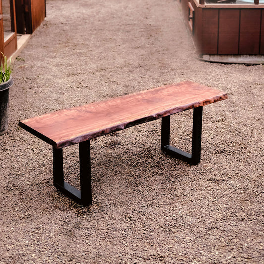 Wooden bench with black metal legs on a gravel surface